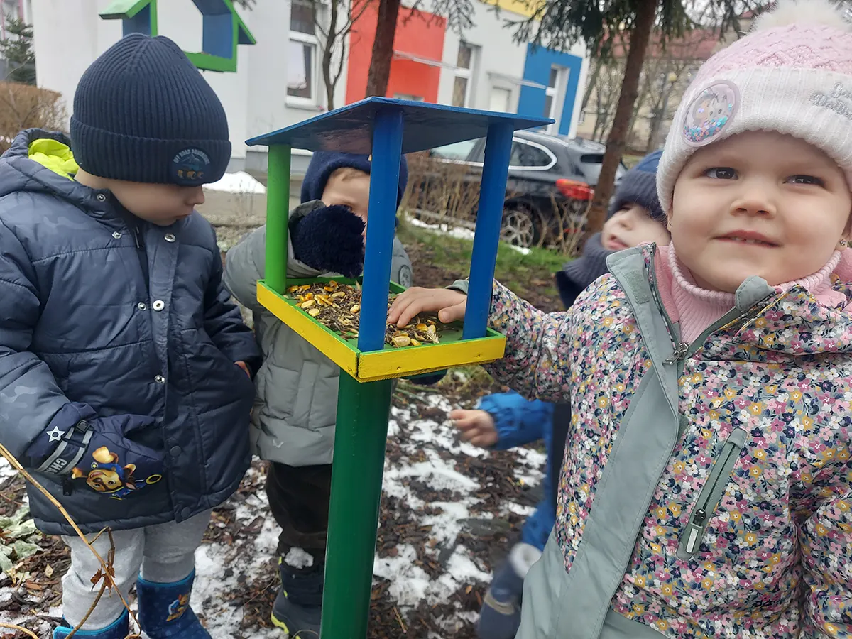  Dzieci obok karmnika dla...