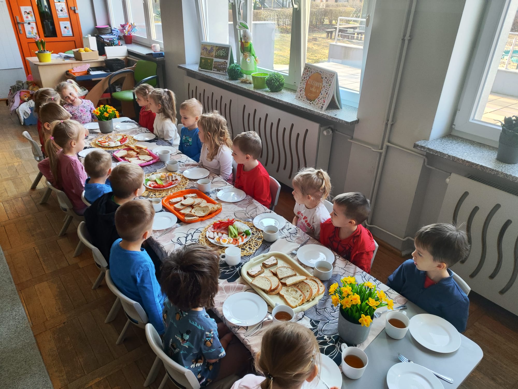  Dzieci siedzą przy stołac...