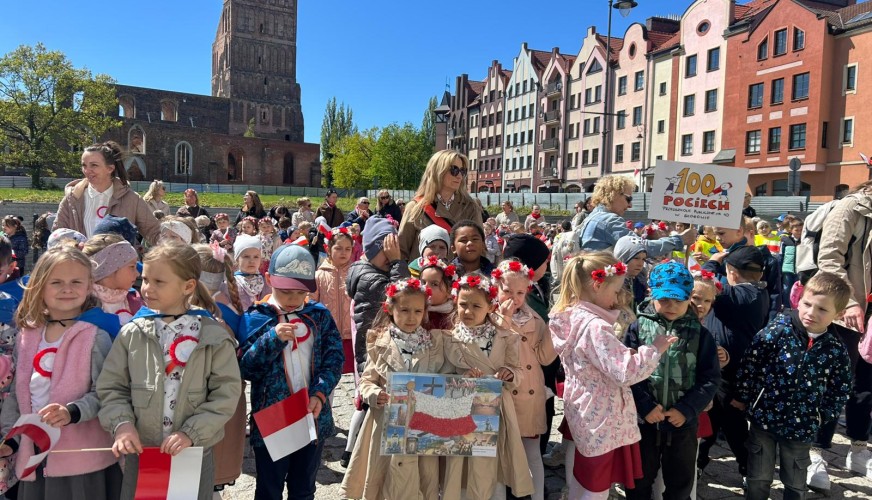 Grupa dzieci z przedszkola trzyma polskie flagi i obrazki Polski