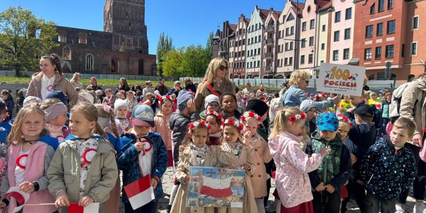 Grupa dzieci z przedszkola trzyma polskie flagi i obrazki Polski