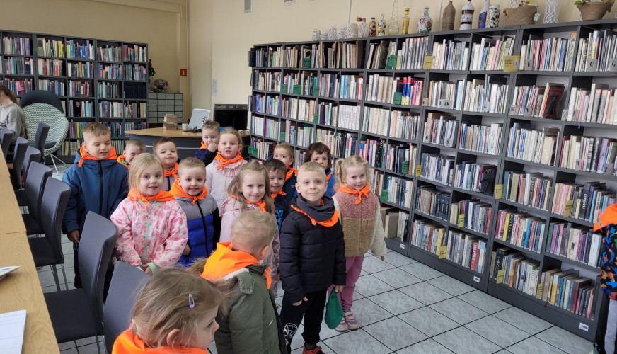 Grupa około 20 dzieci w pomarańczowych kamizelkach odblaskowych.